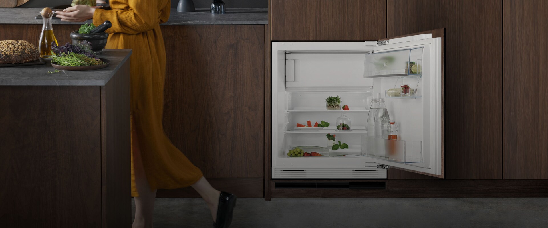 Henkilö kulkee avoimen jääkaapin oven ohi.